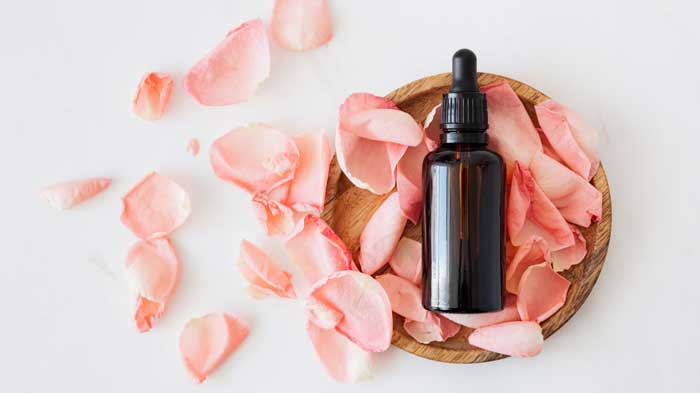 Bottle of serum or oil in a wooden basket with rose petals