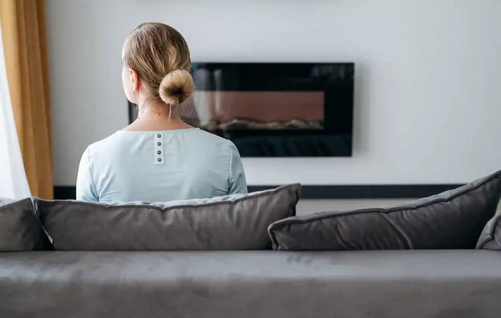 Back View of a Woman Sitting on Gray Couch, With a Chimney in Front of Her