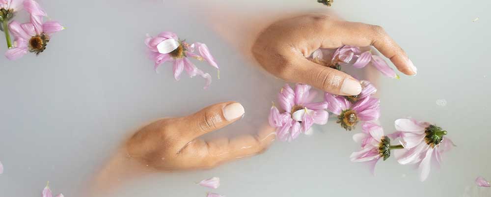 Woman's hands touching gentle flowers in water